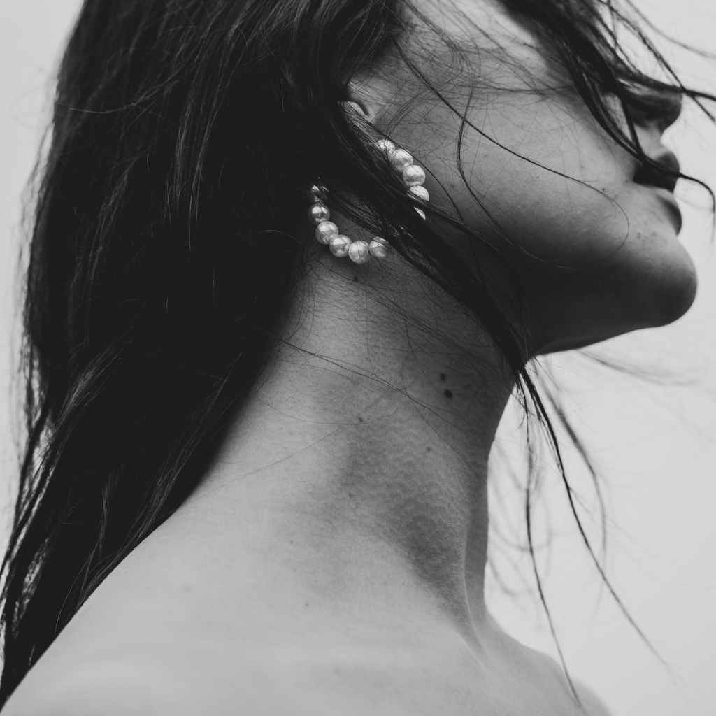a woman with long hair wearing a peral hoop earring