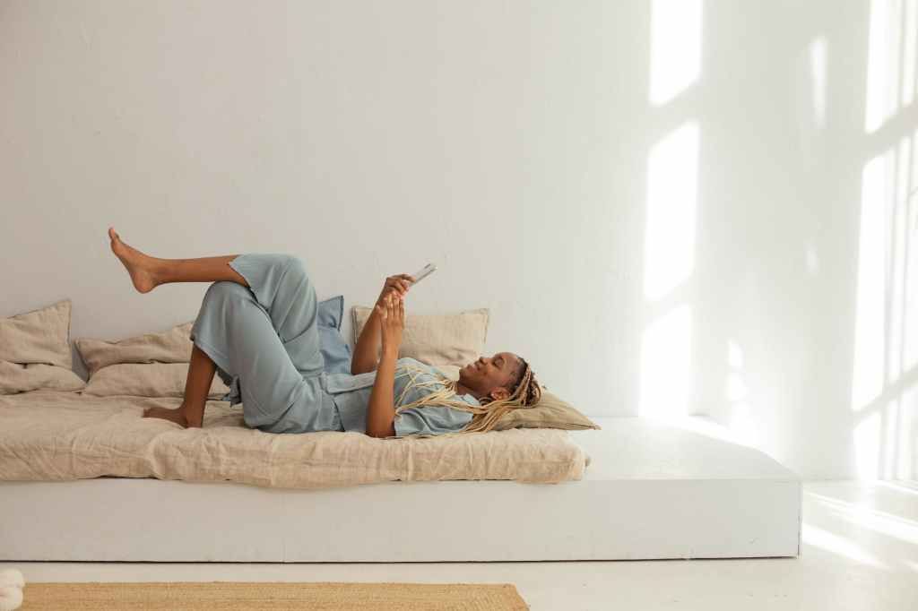 woman lying in bed using smartphone